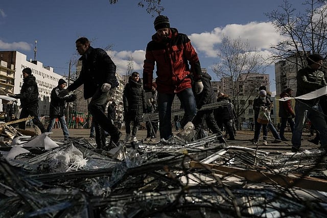 People clear debris outside a medical center damaged after parts of a Russian missile, shot down by Ukrainian air defense, landed on a nearby apartment block, according to authorities, in Kyiv, Ukraine. ( Photo |AP)
