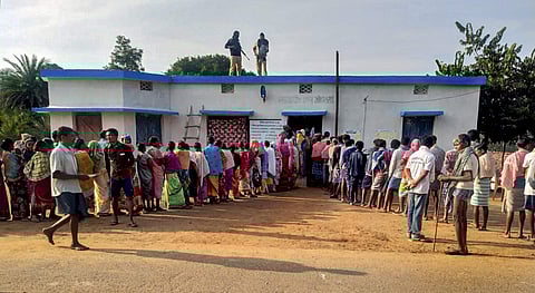 Security personnel stand guard as voters wait in queues to cast their votes during the first phase of Assembly elections in Chhattisgarh. (Photo| PTI)
