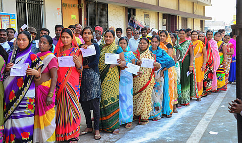 Voters stand in a queue at a polling station to cast their votes for the 2nd phase of Assembly elections in Raipur. (Photo| PTI)