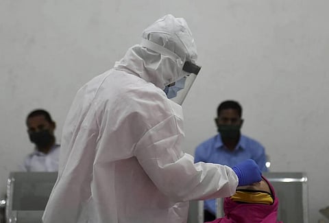 A health worker collects swab sample of a woman for Covid-19 testing at Dadar in Mumbai. (Photo | PTI)