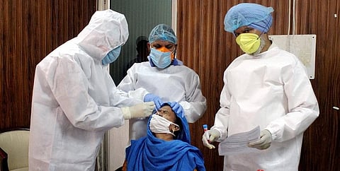 Medics collect a swab sample of a sweeper for COVID-19 testing at MCD office, during the ongoing nationwide lockdown, in Patiala. (Photo | PTI)