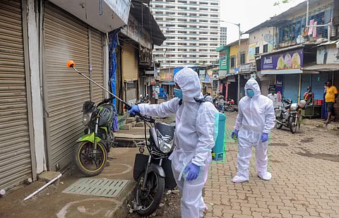 A health worker sprays disinfectant on closed shops at Appa Pada slum area in Mumbai Friday June 26 2020. (Photo | PTI)
