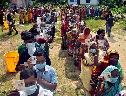 Voters show their ID cards while standing in queues during the 3rd phase of voting for the West Bengal assembly election, in Howrah. (Photo | ANI)