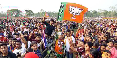 BJP supporters hold party flags during an election rally of PM Narendra Modi ahead of the Assam assembly elections in Tinsukia. (File Photo| ANI)