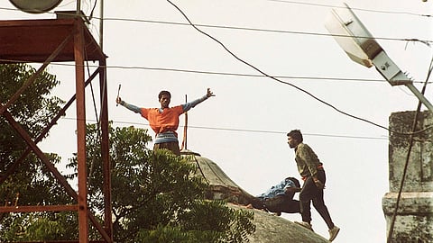 Hindu hard-liners stand on top of one of the three domes of the 16th century Babri mosque before it was destroyed in Ayodhya, India, Dec. 6, 1992.