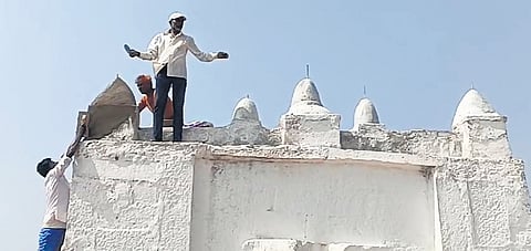 Labourers get to work reconstructing the damaged religious structure in Tadkod village of Dharwad district on Thursday.