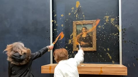 This image grab taken from AFPTV footage shows two environmental activists from the collective dubbed "Riposte Alimentaire" (Food Retaliation) hurling soup at Leonardo Da Vinci's "Mona Lisa" painting, at the Louvre museum in Paris.