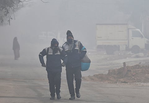 Pedestrians walking outdoors despite heavy smog in Delhi.