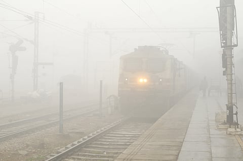 A train runs on the track amid the dense fog at the railway station on a cold winter morning, in Amritsar on Wednesday.
