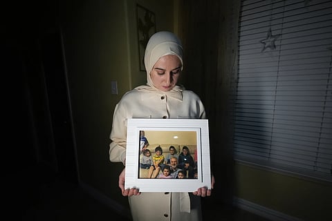 Maryam Kamalmaz hold a photo of her father with some of his 14 grandchildren in Grand Prairie, Texas, Jan 17, 2024.