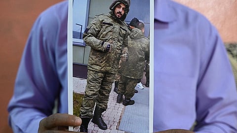 This photo taken on February 22, 2024 shows a picture printout of Indian national Mohammed Asfan, seen wearing Russian military fatigues, who last called family from the southern Russian city of Rostov-on-Don before being deployed amid the conflict in Ukraine, being held by his brother Mohammed Imran in Hyderabad.