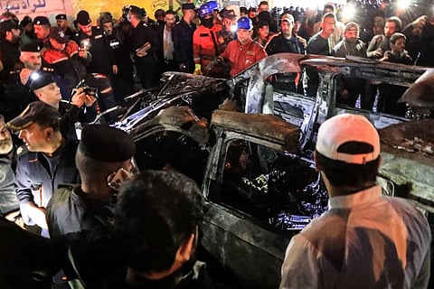 People, rescuers and security forces gather around a vehicle hit by a drone strike, reportedly killing three people, including two leaders of a pro-Iran group, in Baghdad.