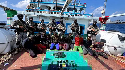 This handout photograph taken on January 30, 2024 and released by the Indian Navy shows Indian commandos stand guard with a group of detained pirates