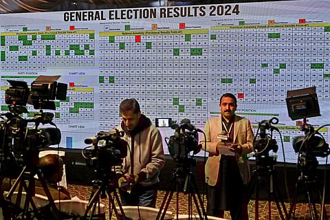 Television journalists report from in front of a screen showing live results in the Election Commission office in Islamabad on February 9, 2024, a day after Pakistan's national elections.