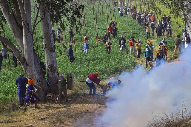 Farmers look for cover after police fired tear gas at them during their 'Delhi Chalo' march, near the Punjab-Haryana Shambhu border, in Patiala district, Wednesday, Feb. 21, 2024.