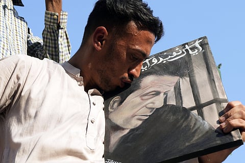 A supporter of imprisoned Pakistan's former Prime Minister Imran Khan's kiss the portrait of his leader