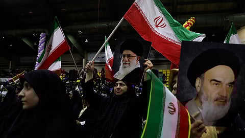 Iranian women wave their country's flags as they hold posters of the Supreme Leader Ayatollah Ali Khamenei, center, and the late revolutionary founder Ayatollah Khomeini during an election campaign rally ahead of the March 1, parliamentary and Assembly of Experts elections, in Tehran, Iran, Tuesday, Feb. 27, 2024.