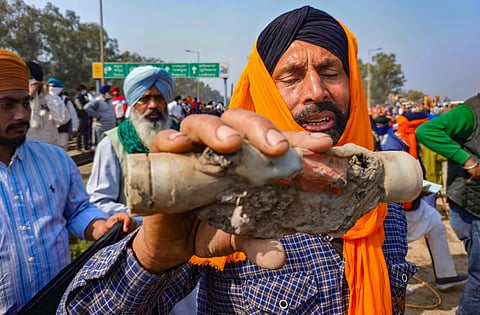 A farmer shows a tear gas shell fired by the police to disperse protesting farmers gathered at the Punjab-Haryana Shambhu border.
