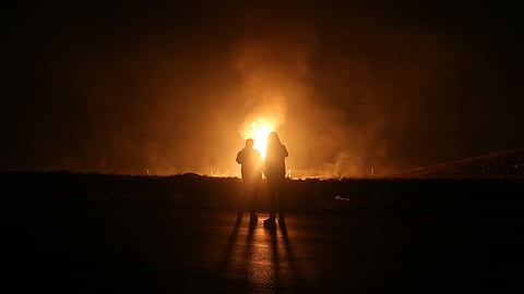 Two men look at flames after a natural gas pipeline explodes outside the city of Boroujen in the western Chaharmahal and Bakhtiari province, Iran, in early Wednesday, Feb. 14, 2024.