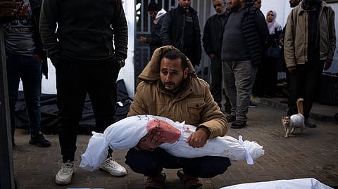 A man holds the body of his daughter who was killed in the Israeli bombardment of the Gaza Strip, at a hospital morgue in Rafah.