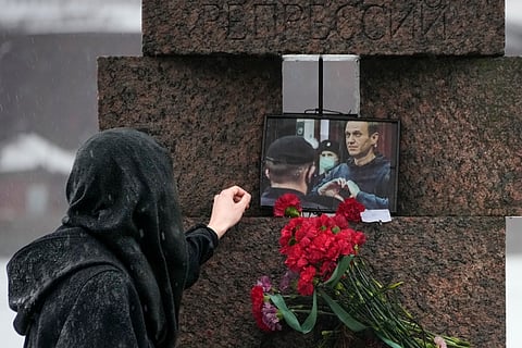 A woman touches a photo of Alexei Navalny after laying flowers paying the last respect to him at the Memorial to Victims of Political Repression in St. Petersburg, Russia on Saturday, Feb. 17, 2024.