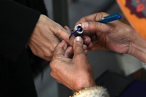 An election official ink marks the thumb of a woman after she casted her vote at a polling station during Pakistan's national elections in Lahore on February 8, 2024.