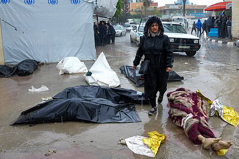 A woman walks between the dead bodies of Palestinians killed in the Israeli bombardments of the Gaza Strip in front of the mortuary at Al Aqsa Hospital in Deir al Balah, Gaza Strip, on Sunday, Feb. 18, 2024.