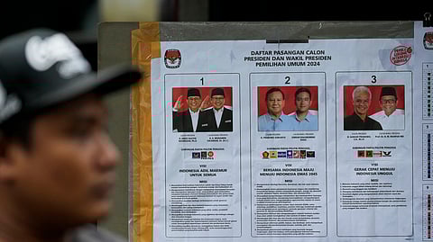 A man walks past a poster with portraits of candidates (L-R) Anies Baswedan and his running mate Muhaimin Iskandar, Prabowo Subianto and his running mate the eldest son of Indonesian President Joko Widodo Gibran Rakabuming Raka, and Ganjar Pranowo and his running mate Mahfud MD.