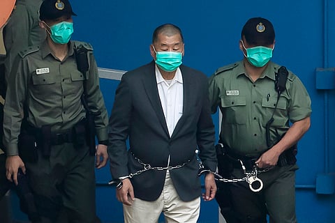 Jimmy Lai is escorted by Correctional Services officers to get on a prison van before appearing in a court in Hong Kong, Dec. 12, 2020.