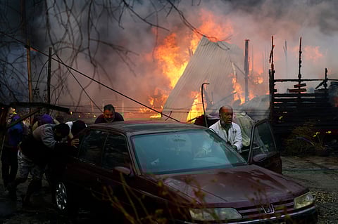Residents push a car away from a burning forest fire engulfing homes in Chile.