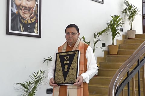 Uttarakhand Chief Minister Pushkar Singh Dhami leaves from his residence with a copy of the Constitution, in Dehradun.