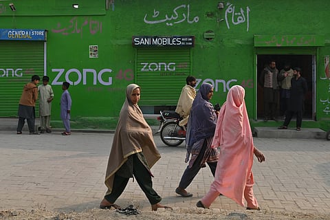 Women look on as they walk along a street in Dhurnal of Punjab Province, ahead of the upcoming general elections.