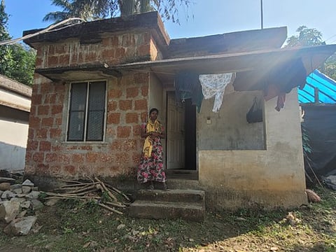 Sandhya, life mission beneficiary from tribal community in Churuli tribal colony, Kalpetta standing infront of here unfinished house