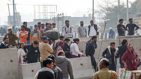 People make their way through concrete barricades installed as part of security arrangements near the Singhu border in view of farmers' 'Delhi Chalo' march, in New Delhi, Wednesday, Feb. 14, 2024.