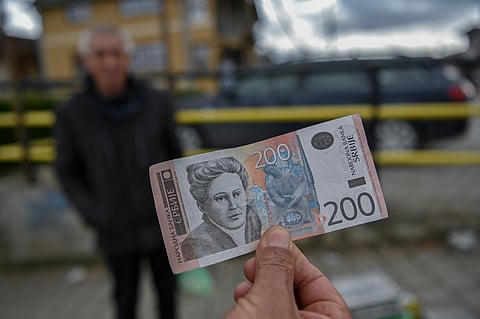 A street vendor shows Serbian Dinar banknotes in the town of Gracanica, central Kosovo.