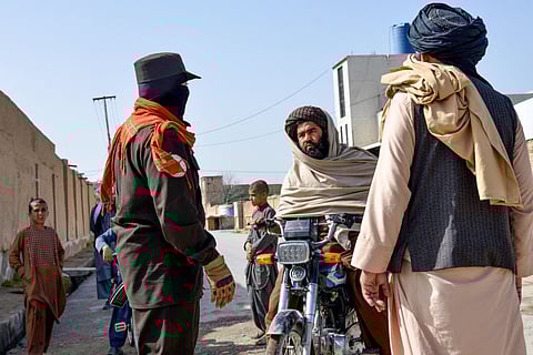An Afghan security personnel checks a motorbike rider near the site of a suicide bomb attack in Kandahar.