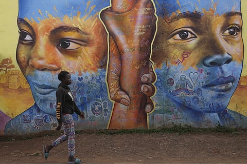 A woman walks past an informational mural against gender-based violence, on a street in Nairobi, Kenya, Wednesday, March 6, 2024.