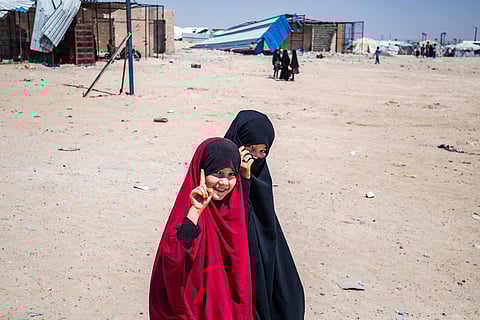 Children gesture as they walk through the al-Hol camp in Syria's northeastern Al-Hasakah Governorate.