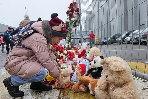 A child places a toy at the fence next to the Crocus City Hall, on the western edge of Moscow, Russia, Saturday, March 23, 2024, following an attack Friday, for which the Islamic State group claimed responsibility.