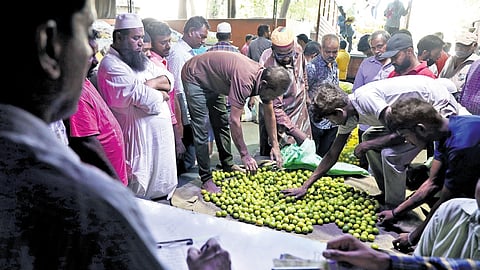 Retailers gather as a vendor auctions lemons at a wholesale market near Darul Shifa Circle in Hyderabad on Sunday. The onset of summer has led to a spike in the price of lemons in the state