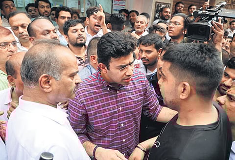 BJP MPs from Bengaluru Tejasvi Surya and PC Mohan speak to the shopkeeper, who was assaulted at his shop in the city on Monday