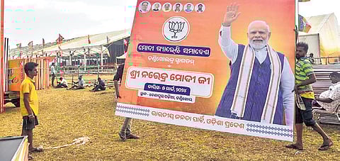 Workers carrying a hoarding of Prime Minister Narendra Modi ahead of his public meeting at Chandikhole in Jajpur, on Monday