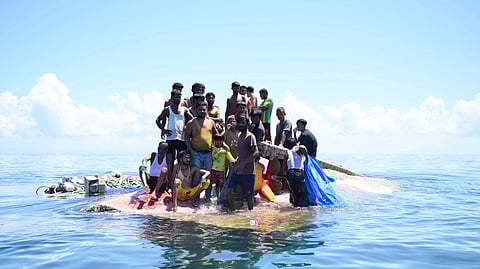 Rohingya refugees stand on their capsized boat before being rescued in the waters off West Aceh, Indonesia, Thursday, March 21, 2024.