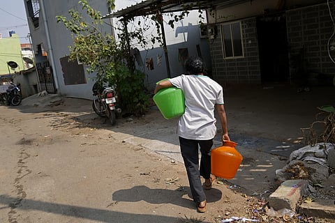 A woman carries home pots filled with potable water collected from a private tanker in Bengaluru, March 11, 2024.
