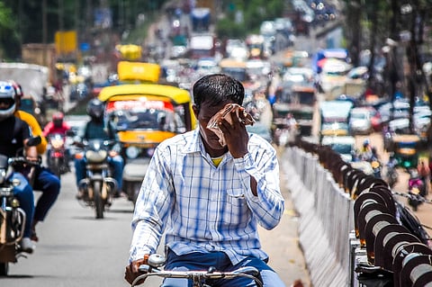 As temperature rises on the onset of summer, a man wipes off sweat from his face while riding a bicycle on NH 16 near Rasul in Bhubaneswar.