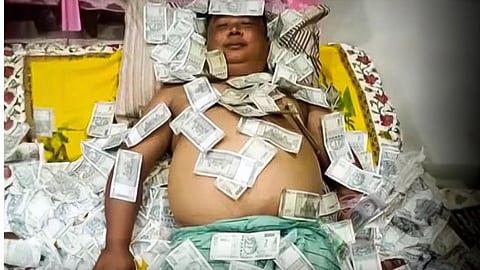 In the viral photo, a man identified as Benjamin Basumatary is seen lying on a bed of currency.
