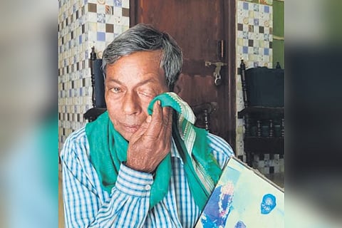 An emotional Rabindra Mallick holding Rout’s photo at Mallipur
