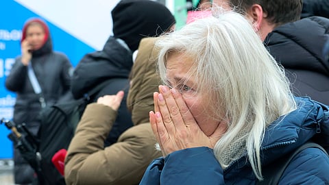 A woman reacts as she place flowers by the fence next to the Crocus City Hall, on the western edge of Moscow, Russia.