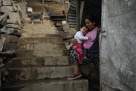 Justina Flores holds her grandchild Maria Paz while resting in the entrance of her home in the Pamplona Alta area in Lima, Peru, March 8, 2024.