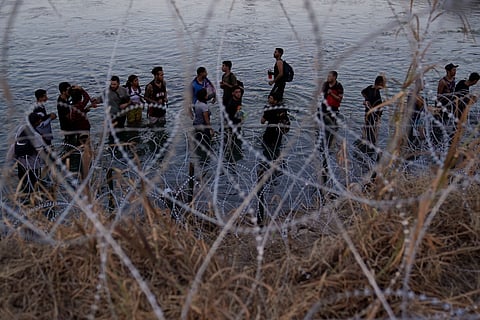 Migrants wait to climb over concertina wire after they crossed the Rio Grande and entered the U.S. from Mexico, Sept. 23, 2023, in Eagle Pass, Texas.